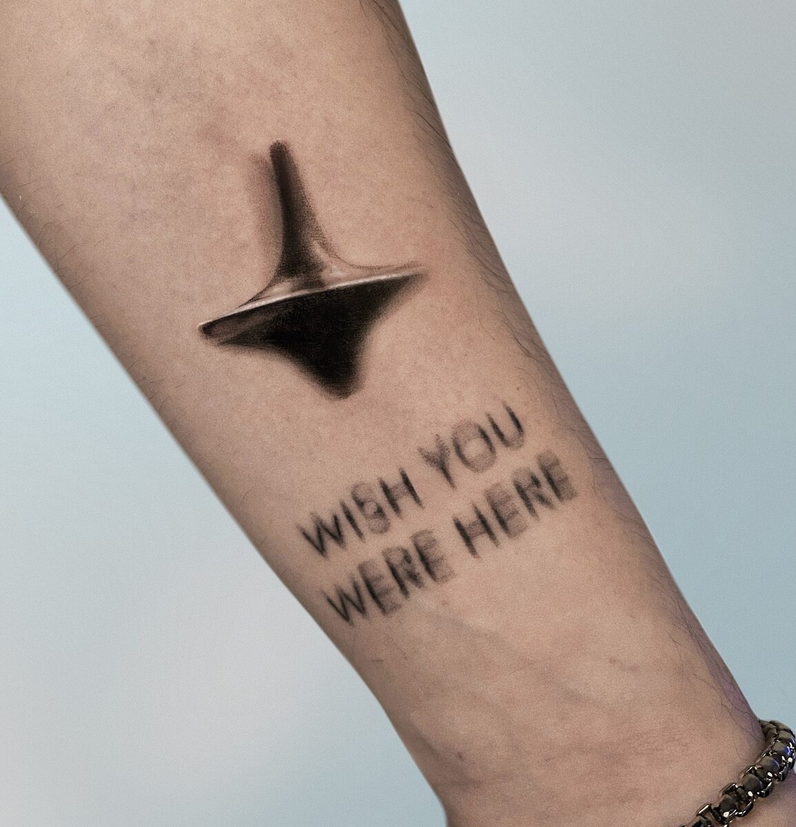 Peonza de Inception con frase WISH YOU WERE HERE difuminada, microrealismo